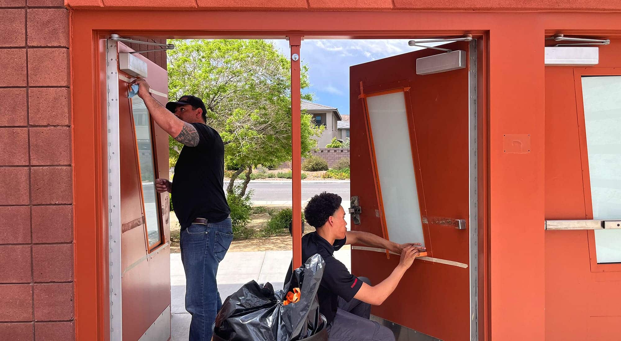 Clear-Armor installation professionals securing bullet-resistant laminate on exterior door windows.